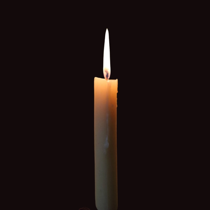 lit beeswax dinner candle on a black background