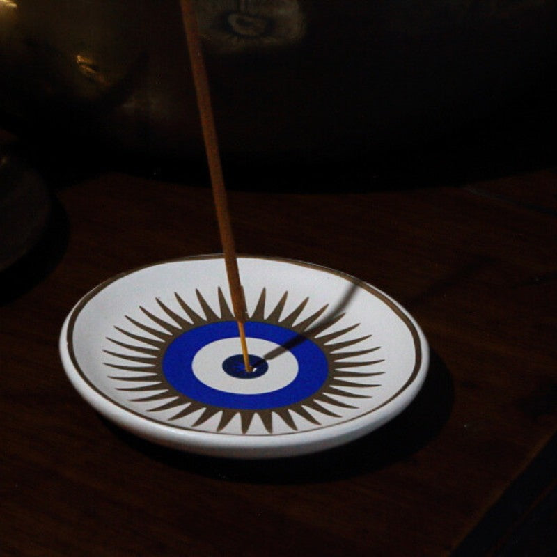 Incense stick on a decorative plate with a blue and white design