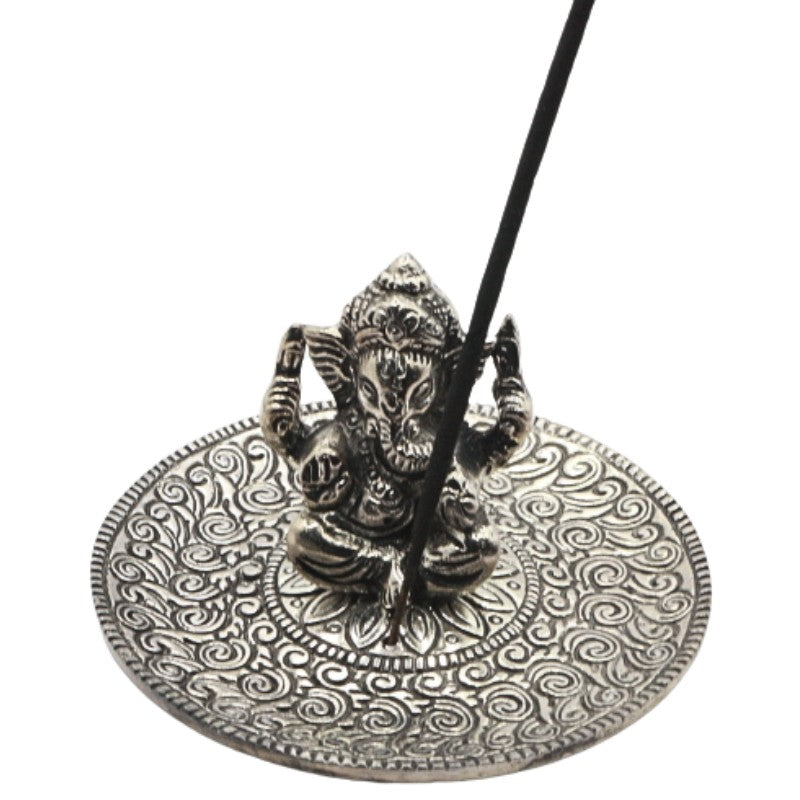 incense stick sitting in an aluminium incense burner with a state of ganesh in the centre