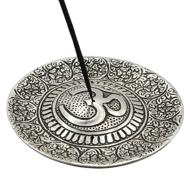 incense stick in the centre of a round aluminium incense burner with om symbol