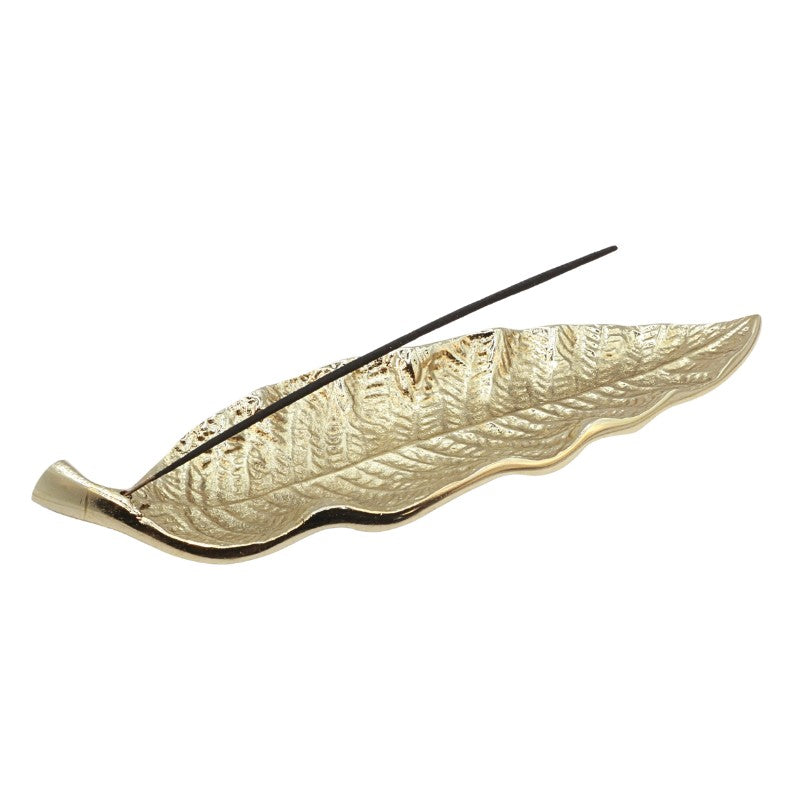 gold incense holder in the shape of a leaf holding a natural incense stick