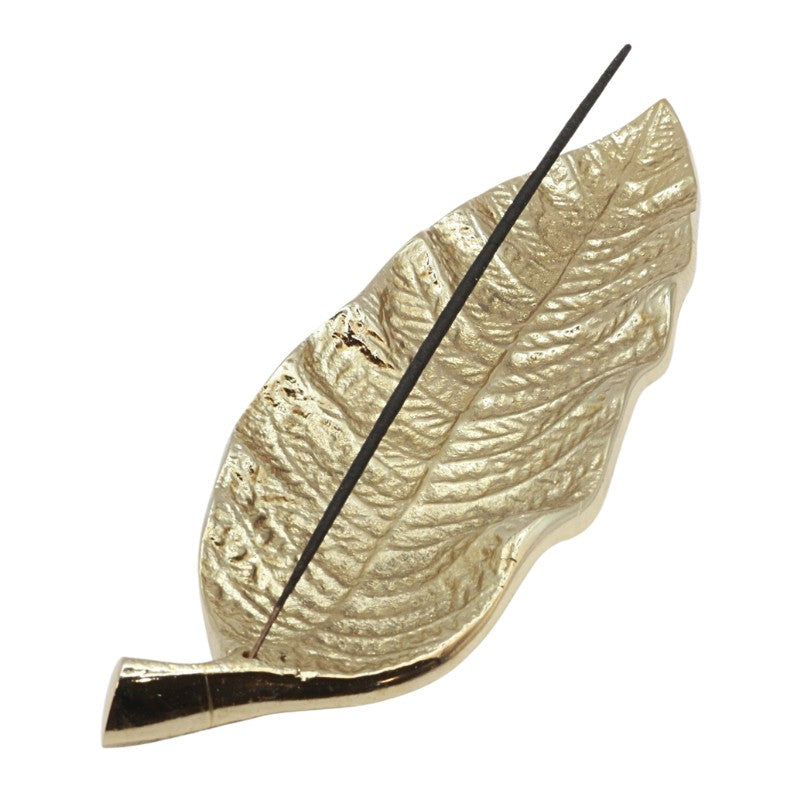 gold incense holder in the shape of a leaf holding a natural incense stick