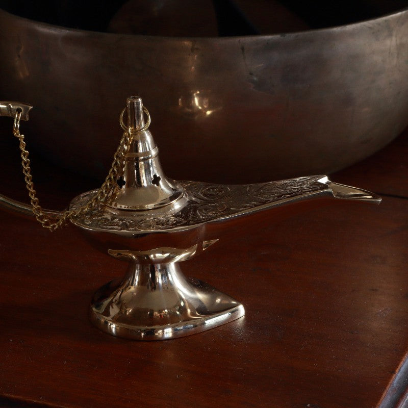 Brass incense cone burner with chain on a wooden surface