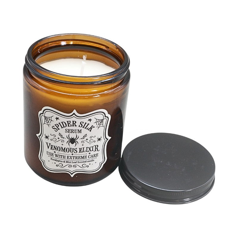 amber coloured jar with white label and spider om front next to a black lid