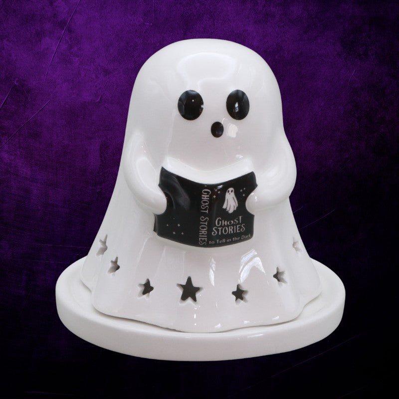 White ghost-shaped candle holder with a book titled 'Ghost Stories' on a purple background