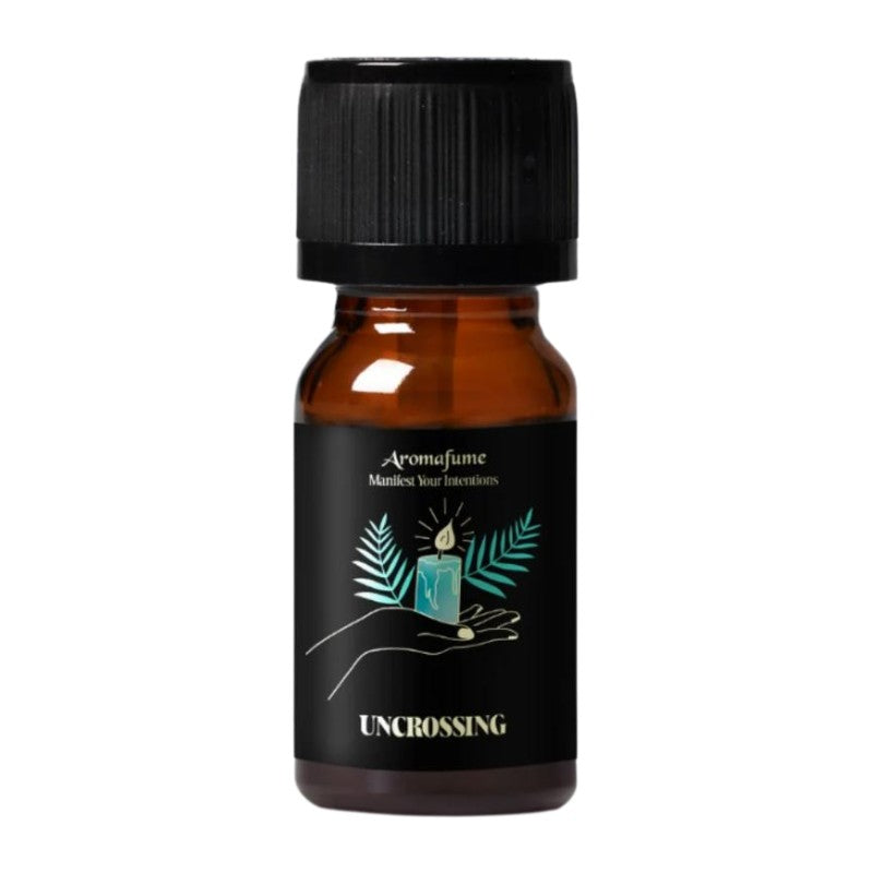 A small amber glass bottle with a black ribbed cap and a black label. The label features a teal candle illustration with palm leaves and the text 'Aromafume', 'Manifest your intentions', and 'UNCROSSING'.