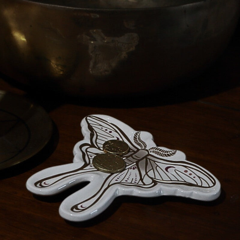 Decorative white dish with butterfly design on a dark surface