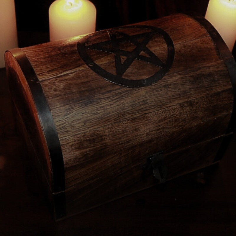 Rustic Wooden Chest with black metal Pentacle on top in front of lit beeswax candles