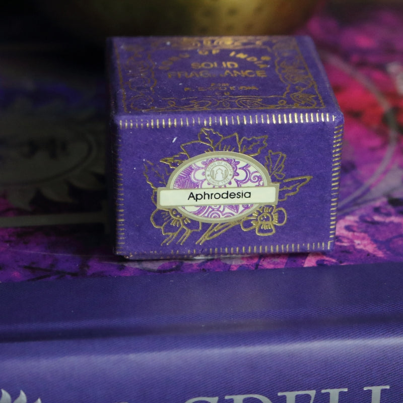 purple and gold box , sitting on a purple and pink book of spells in front of a brass singing bowl with wooden striker.