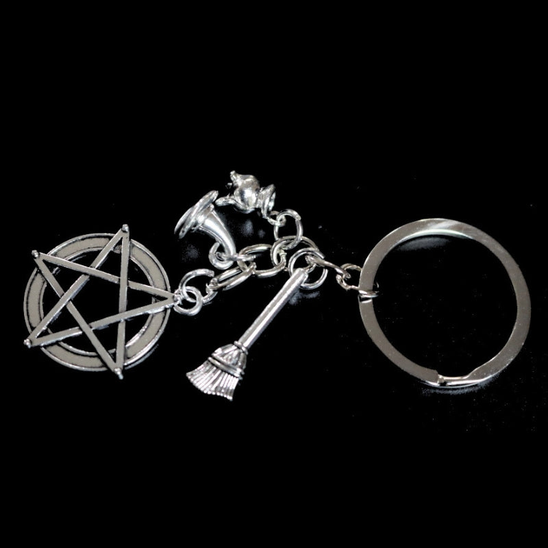 silver coloured key ring with a pentacle (5 pointed star within a circle) , a cauldron , a witches hat and a broom joined to a silver ring by a silver chain.