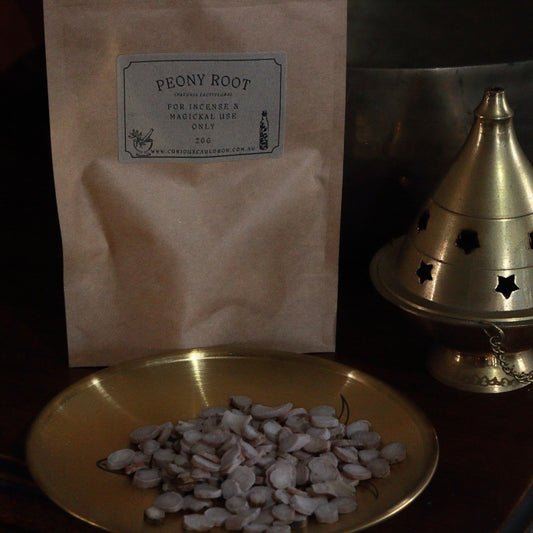 Bag of peony root with a small pile on a plate, next to a brass incense burner.
