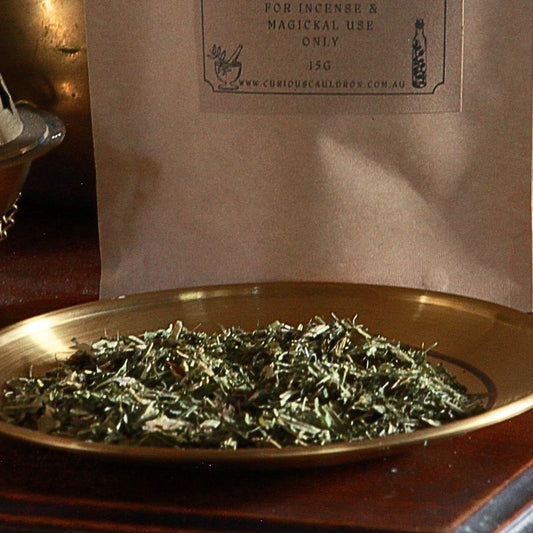 Dry herbs on a gold altar plate with a brown paper bag in the background