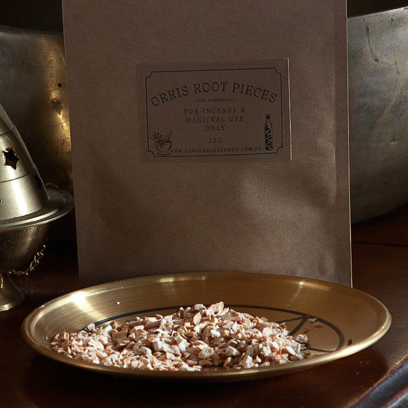 Bag of Orris Root Pieces with a label and a dish of Orris Root on a wooden surface.