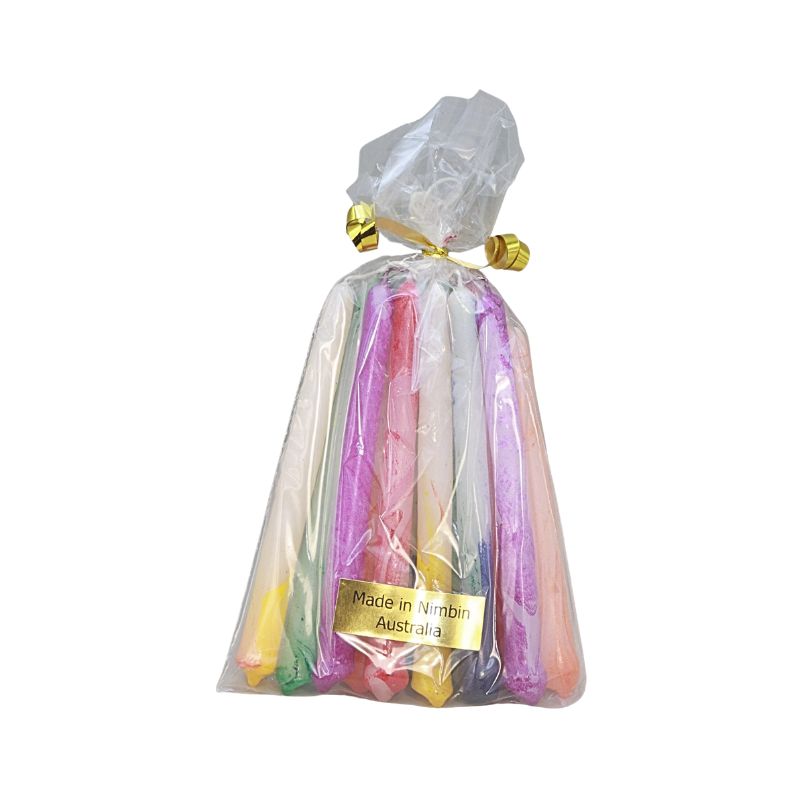 A clear plastic bag containing multiple colourful candles, tied at the top with gold foil, and featuring a gold label that reads 'Made in Nimbin Australia'.