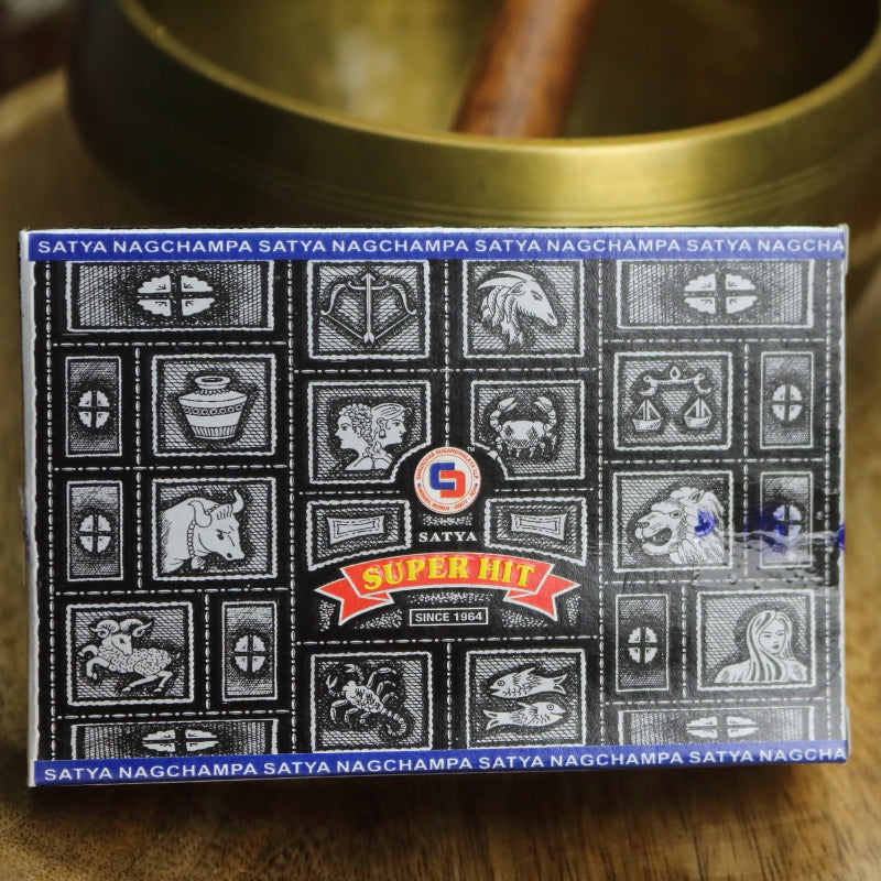 black box of satya backflow incense cones sitting on a wooden table in front of a brass singing bowl with wooden striker