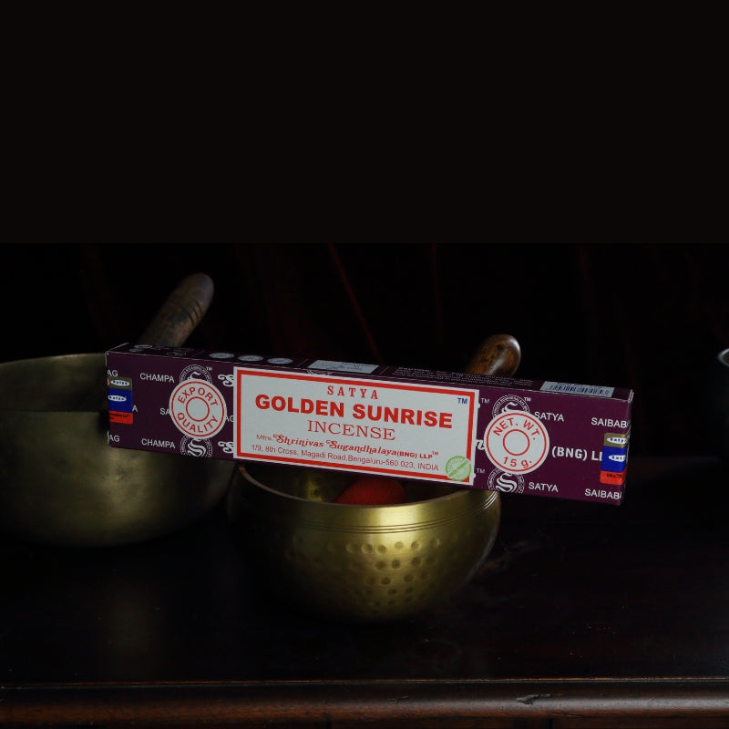 satya incense sticks sitting on a brass singing bowl
