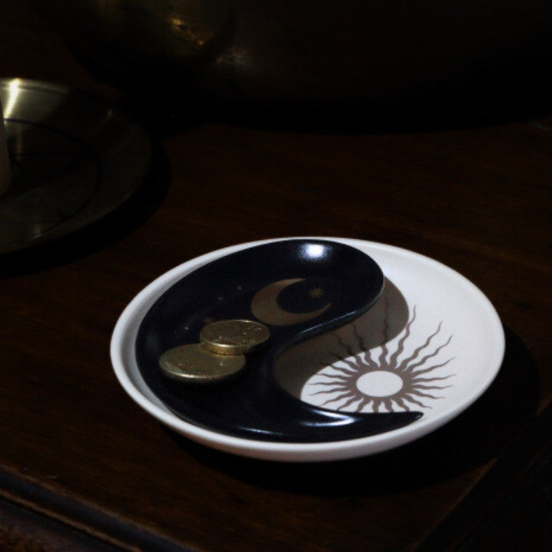 Yin yang symbol stacking  plates with coins in a dark setting
