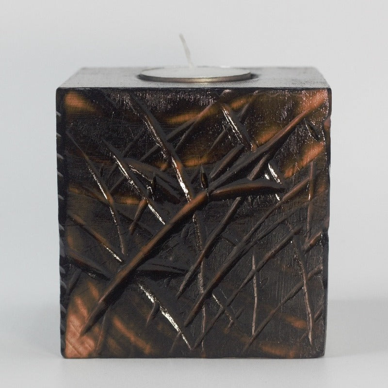 handmade wooden candle holder with etched bamboo design, containing a tea light candle on a white background