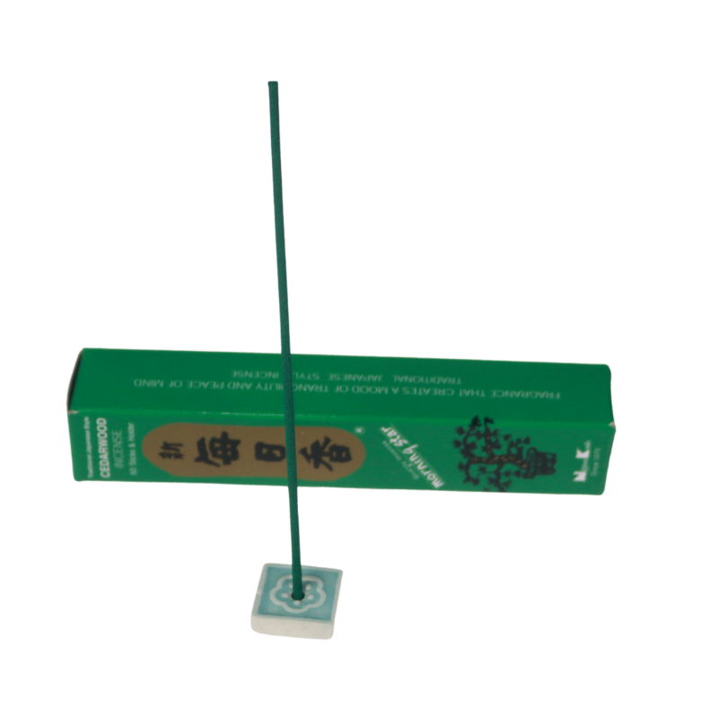 cedarwood incense in a blue and white incense tile in front of a green and gold cedarwood incense box