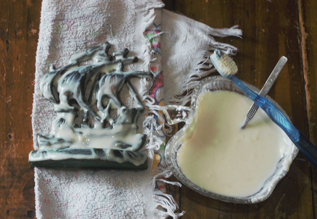 vintage brass bookend on white tea towel next to glass apple shaped bowl containing white paste and teaspoon, sitting on a wooden coffee table