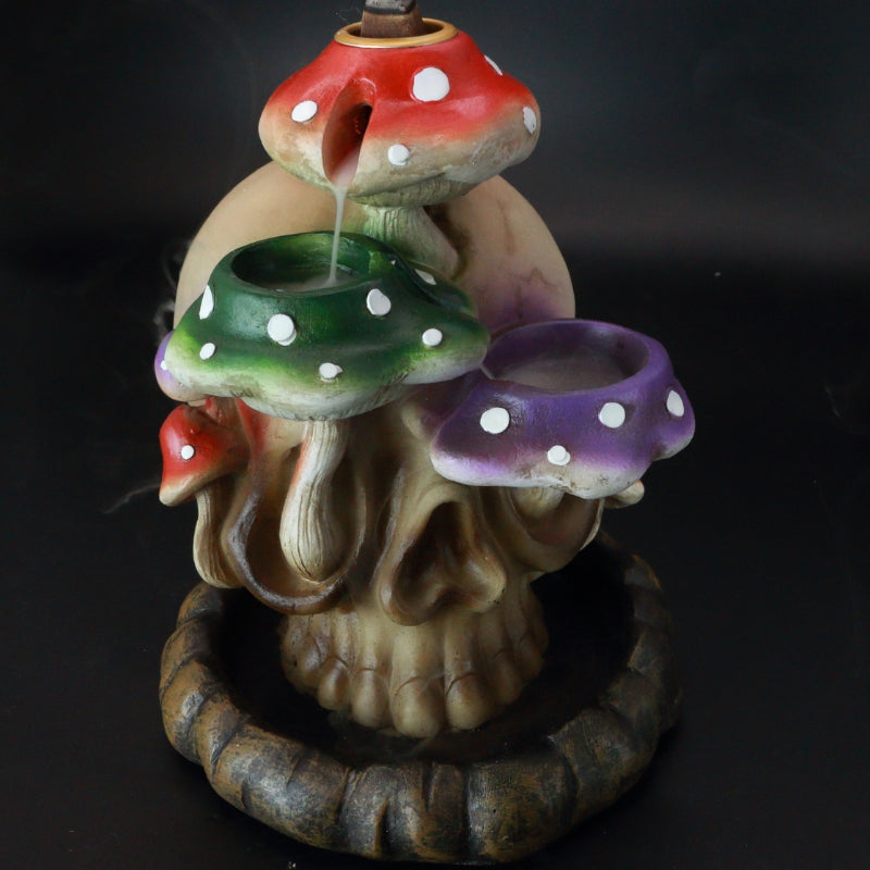 backflow incense cone burner of a skull with colourful mushrooms growing out the side of it, with incense smoke flowing down the mushrooms.