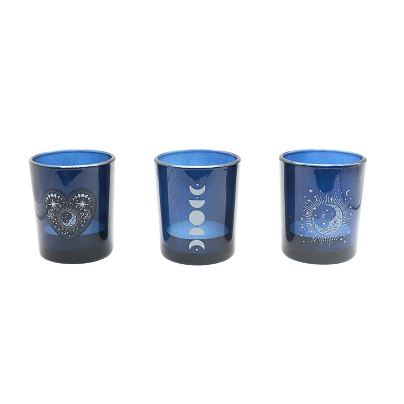 Three blue glass votive holders with celestial designs on a white background