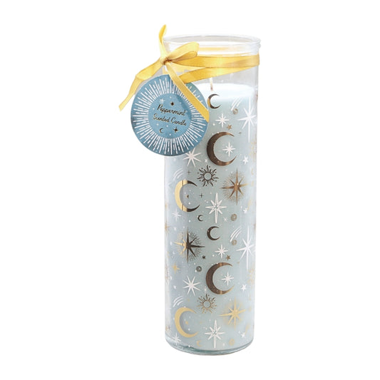 A tall glass jar candle with a pale blue wax body decorated with gold, silver, and white crescent moons and stars. It has a clear glass lid, a yellow ribbon tied in a bow, and a round blue paper tag that reads 'Peppermint Scented Candle'.