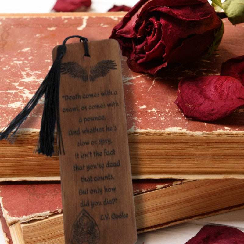 handmade wooden bookmark with black tassel leaning against two old books