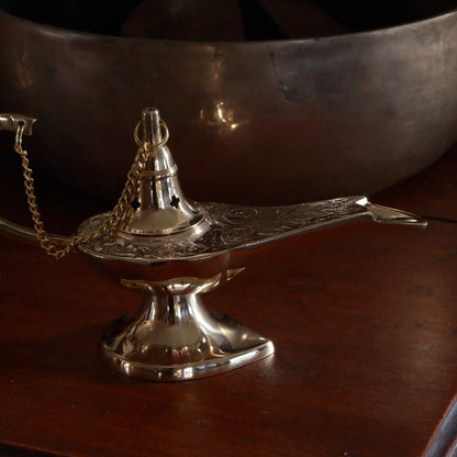 Brass incense cone burner with chain on a wooden surface
