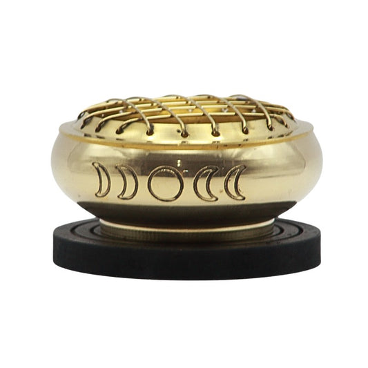 Brass charcoal incense burner engraved with the phases of the moon, sitting on a wooden base plate 