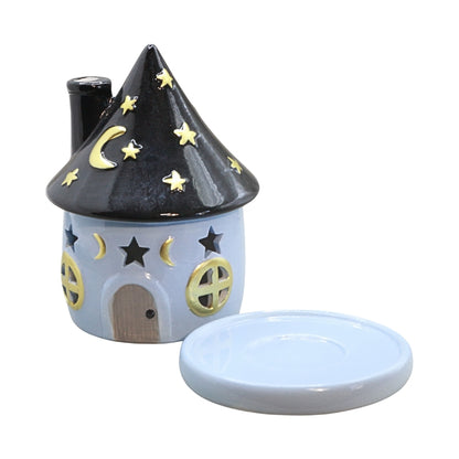 blue round house shaped incense cone holder with gold stars and windows and a grey door, next to a round ceramic plate  on a white background