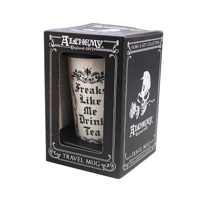 A black Alchemy brand travel mug in its original window box packaging, with the mug inside printed with 'Freaks Like Me Drink Tea' in black gothic lettering on a white background.