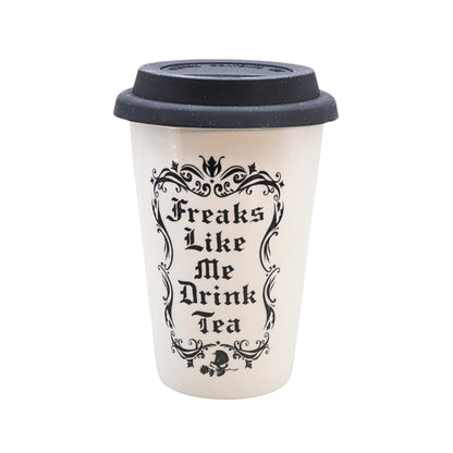 A white reusable coffee cup with a black lid, featuring the text 'Freaks Like Me Drink Tea' in a black gothic font with an ornate frame.