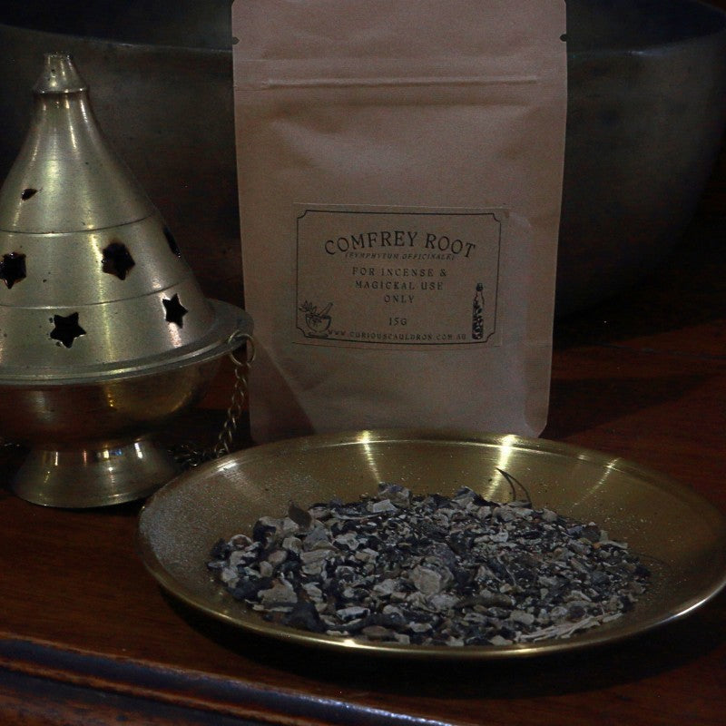 Comfrey root incense on a brass dish with packaging in the background