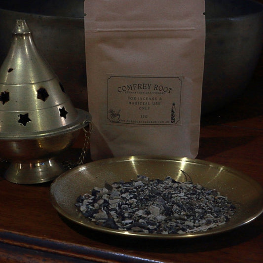 Comfrey root incense on a brass dish with packaging in the background