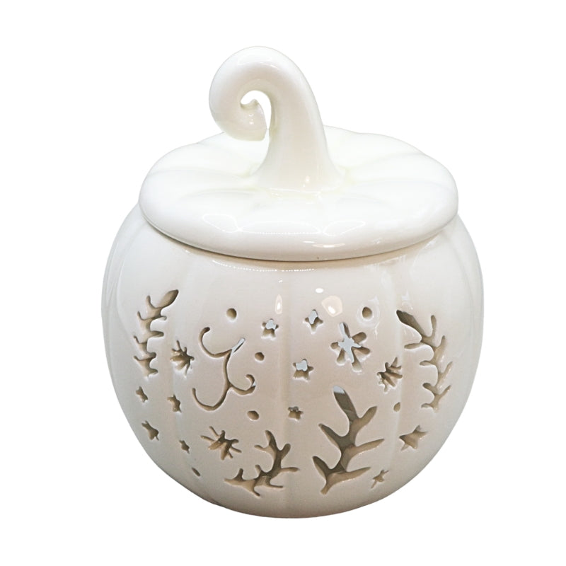 A white ceramic pumpkin-shaped container with a matching lid and a curled top handle, featuring decorative cutout patterns of leaves and stars.
