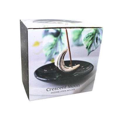 A boxed incense stick holder shaped like a crescent moon, shown in its retail packaging on a plain white background. The front of the box features a photo of the silver crescent moon holder resting on a black stone dish, with the text 'Crescent Moon' and 'INCENSE STICK HOLDER' visible.