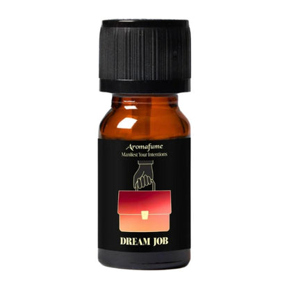 A small amber glass bottle with a black ribbed cap and a black label. The label has a red-to-orange gradient pouch graphic and the text 'Aromafume' and 'DREAM JOB'.