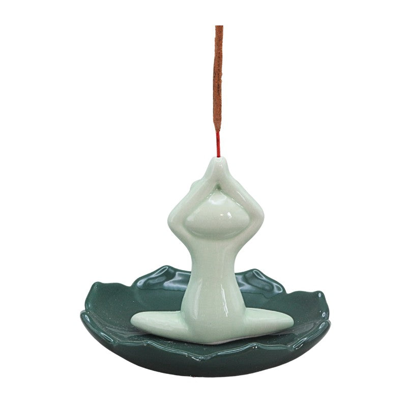 green frog sitting cross legged on lily pad holding incense stick above head