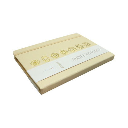 linen cover diary with the chakra symbols printed in gold on the cover. Gold edged pages and a tag with the words "Chakra Flow" and "Notebook" covering it.