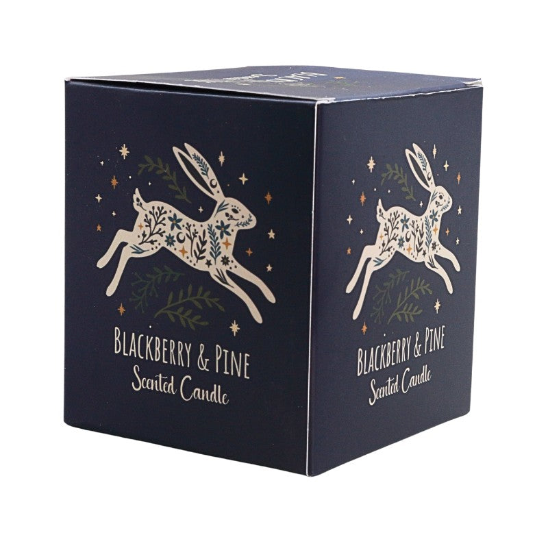 A square navy blue scented candle box with white rabbit illustrations decorated with green leaves and gold stars, labeled 'Blackberry & Pine Scented Candle'.