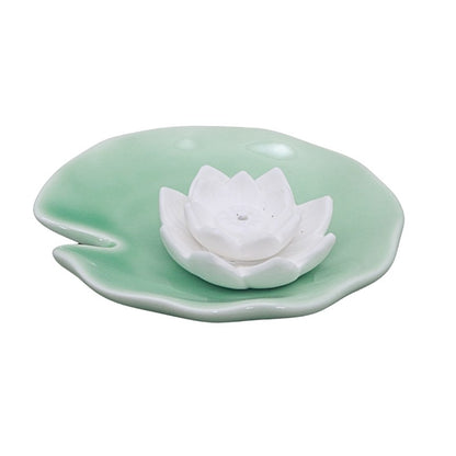 Ceramic white lotus flower on a green leaf with a white background