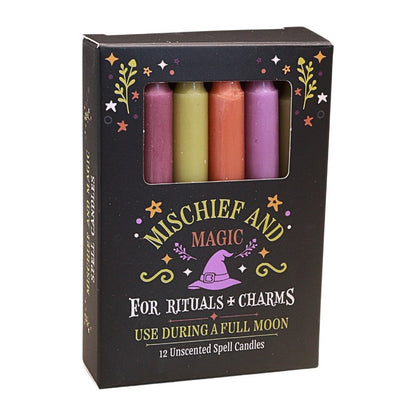 A black box of Mischief and Magic Unscented Spell Candies, featuring a window that displays four colorful wax candles ( yellow-green, orange, and light and dark purple) inside. The packaging is decorated with gold stars, green leaves, and a purple witch hat illustration.