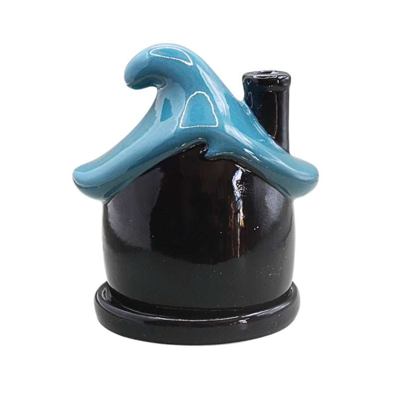 A glossy ceramic pipe shaped like a house with a turquoise blue wave-shaped roof and a dark blue body, shown on a plain white background.
