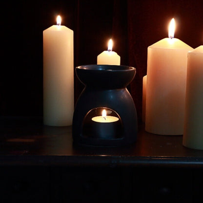 black oil burner.  Lit beeswax pillar candles in the background.