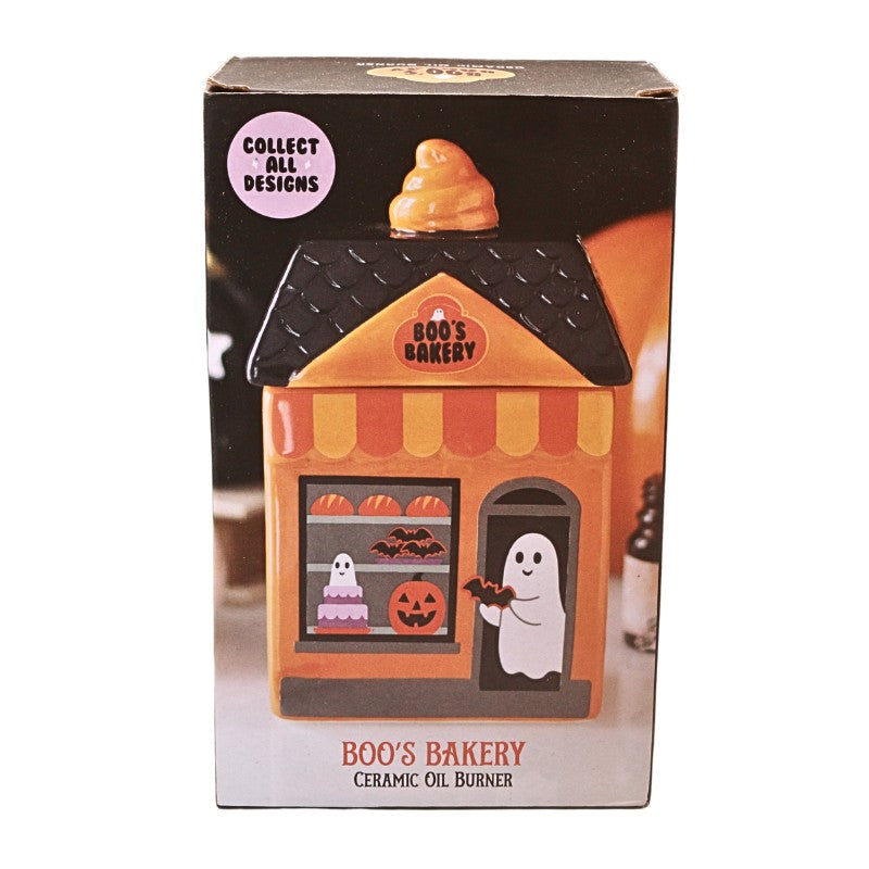 A boxed ceramic oil burner shaped like Boo's Bakery from The Addams Family, shown in its retail packaging against a white background.