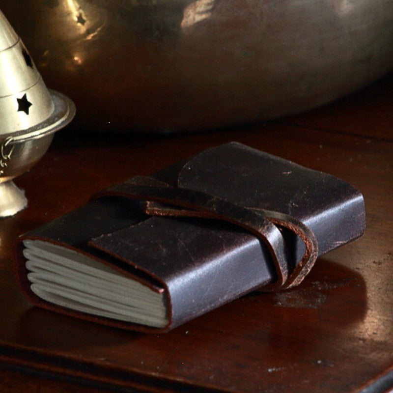 Oiled leather journal with a leather strap on wooden table