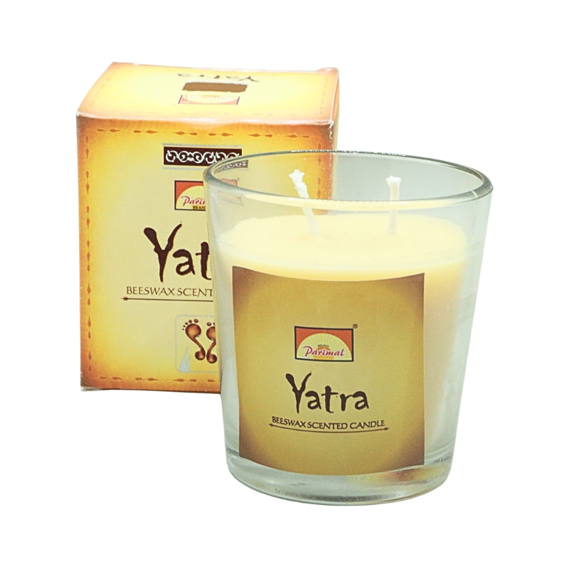 Parimal Yatra beeswax candle with two wicks in a clear glass jar, displayed in front of its gold box.
