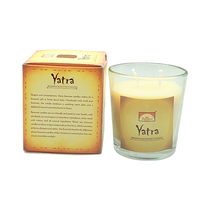 Parimal Yatra beeswax candle in a clear glass jar beside its gold box showing the product description.
