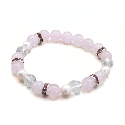 A beaded stretch bracelet featuring light pink rose quartz beads, white faux pearl beads, and clear faceted crystal beads, separated by small metallic spacer rings.